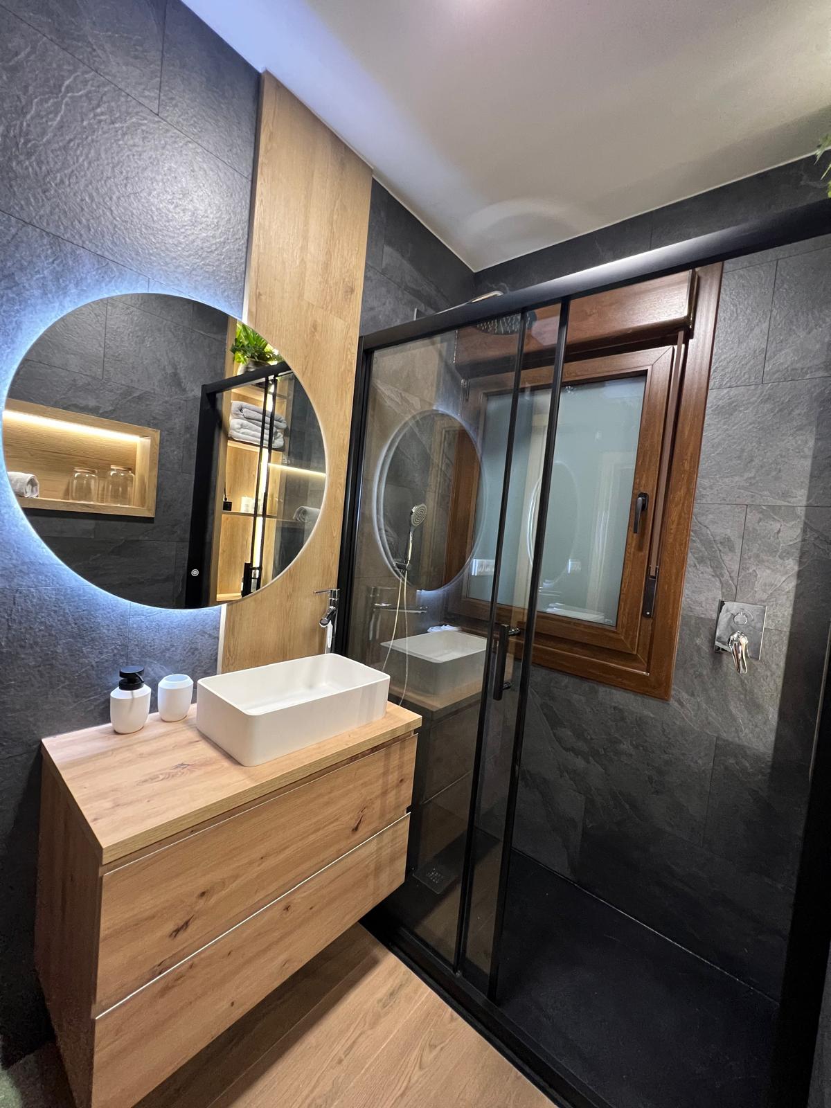 Baño con madera, revestimiento antracita y mampara negra
