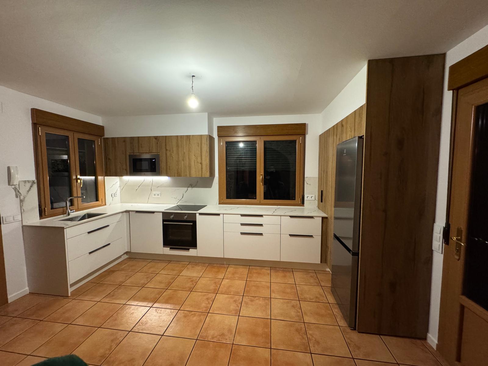 Cocina con frentes blancos, madera y encimera clara